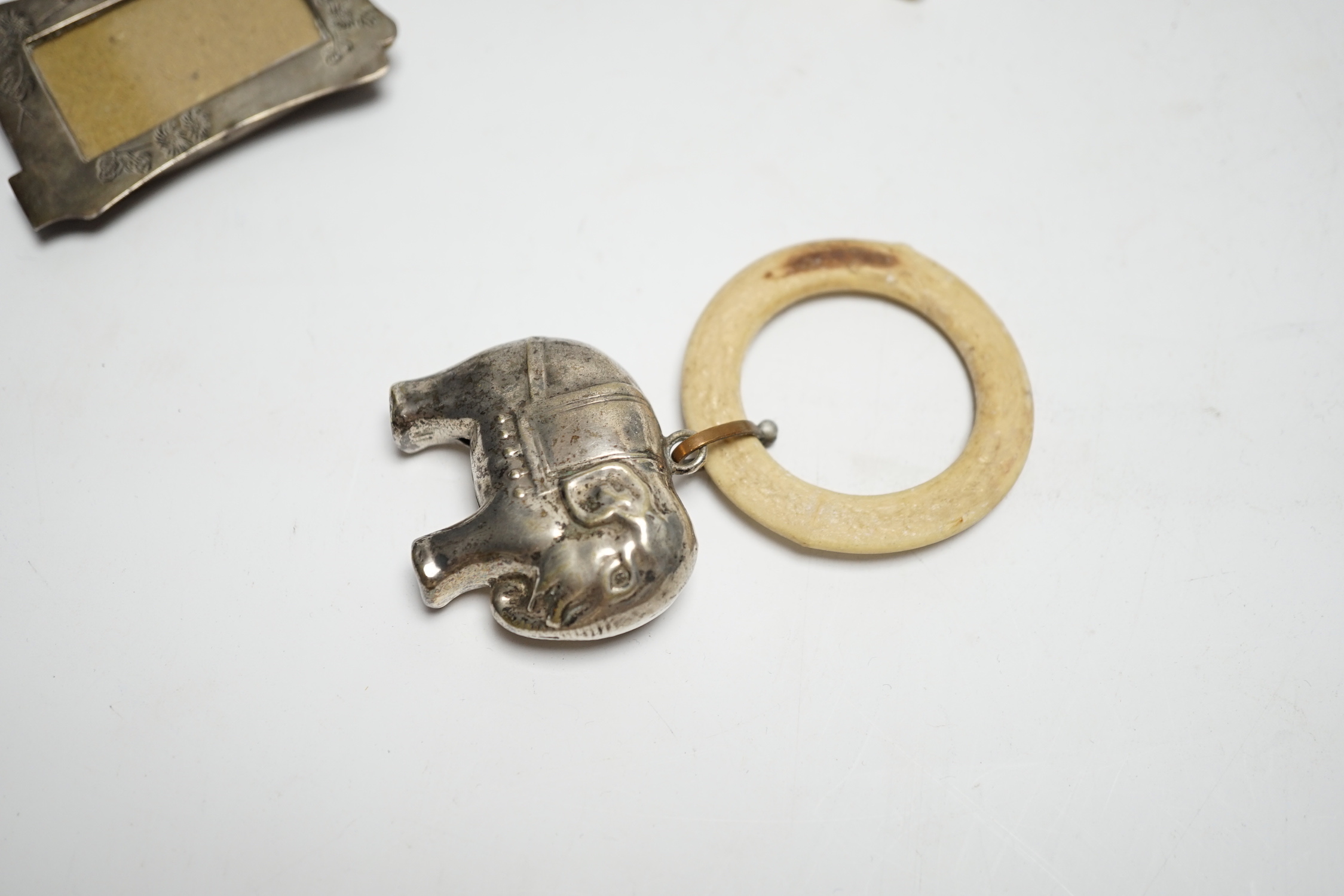 An Edwardian silver and mother of pearl child's rattle, 11cm, together with a miniature white metal photograph frame and a plated child's rattle.